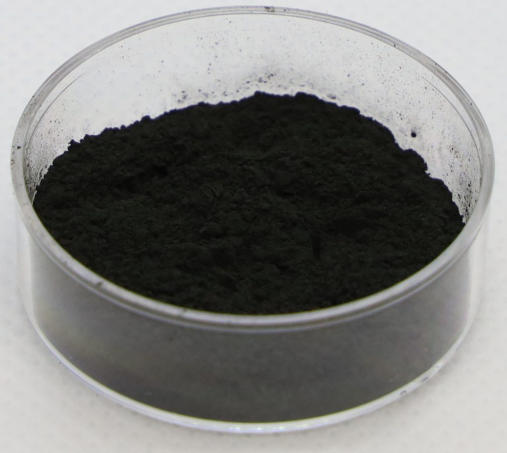 An image of black uranium dioxide (UO2) powder in a glass dish.