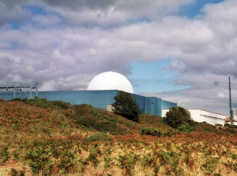 An image of Sizewell B Nuclear Power Station, surrounded by fields. A white dome rises from a blue cube.