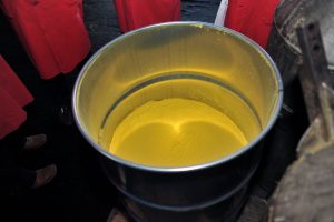 An image of a cylindrical metal barrel containing a yellow powder - yellowcake, a concentrated form of uranium ore.