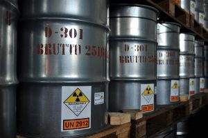 A row of labelled cylindrical barrels, labelled as radioactive and containing yellowcake.