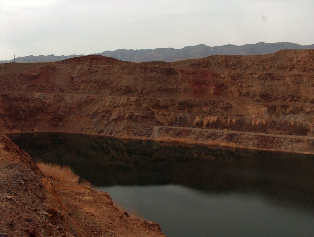 A view of a former open pit mine, with blue water filling the former pit.