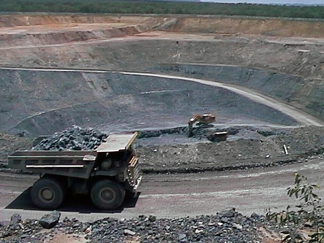 Am image of a digger driving along a track alongside an open-pit uranium mine, in Australia.