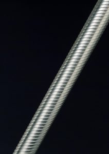 An image of a long and thin fuel rod from an Advanced Gas-Cooled Reactor (AGR) - containing uranium oxide pellets, clad in ribbed shiny beryllium metal.