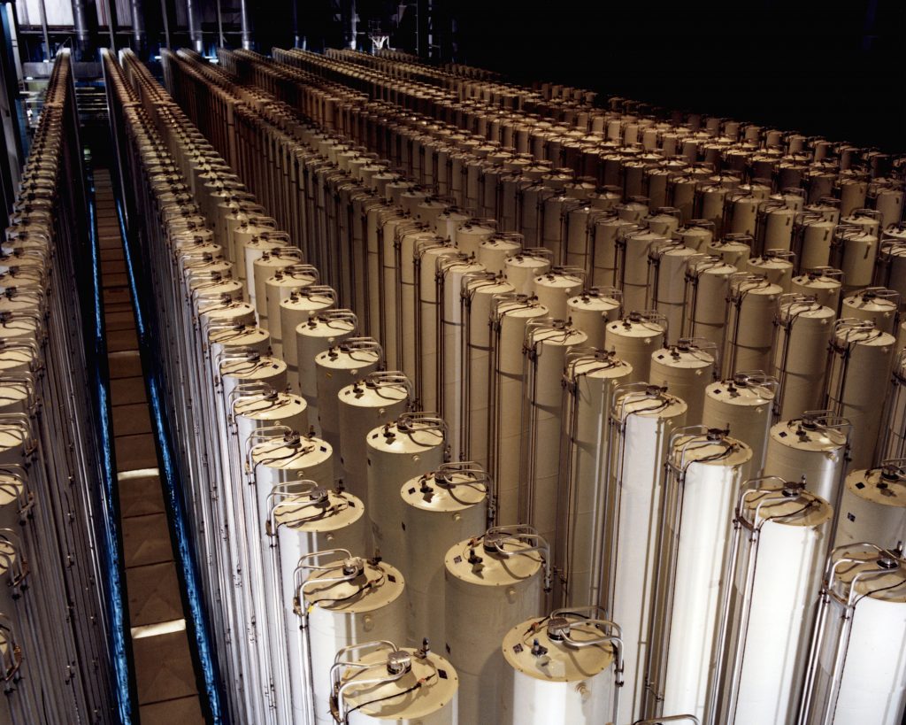 Industrial plant containing hundreds of tall cylindrical gas centrifuges, arranged in rows.