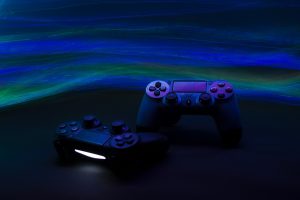 A closeup shot of two game controllers in a dimly lit space