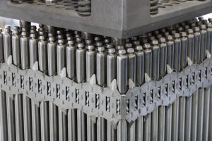 Close-up view of control rods in a nuclear reactor, arranged in a grid pattern with metallic surfaces and dark slots between them. These control rods are essential for regulating the fission reaction in a boiling water reactor by absorbing neutrons and controlling the reactor's power output.