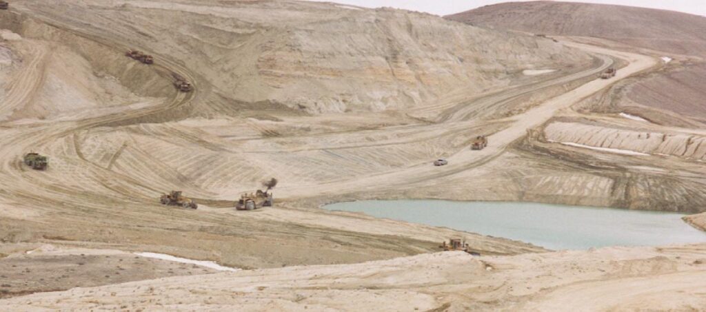 A scenic view of the Sunset Uranium Mine in Wyoming, showing a vast mining landscape with industrial equipment and a warm sunset sky, highlighting uranium mining operations.
