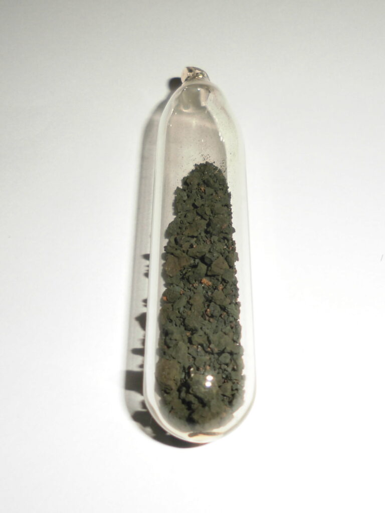 A test tube containing dark granules of triuranium octoxide - the product of leaching, the second stage in milling and refining of uranium ore.