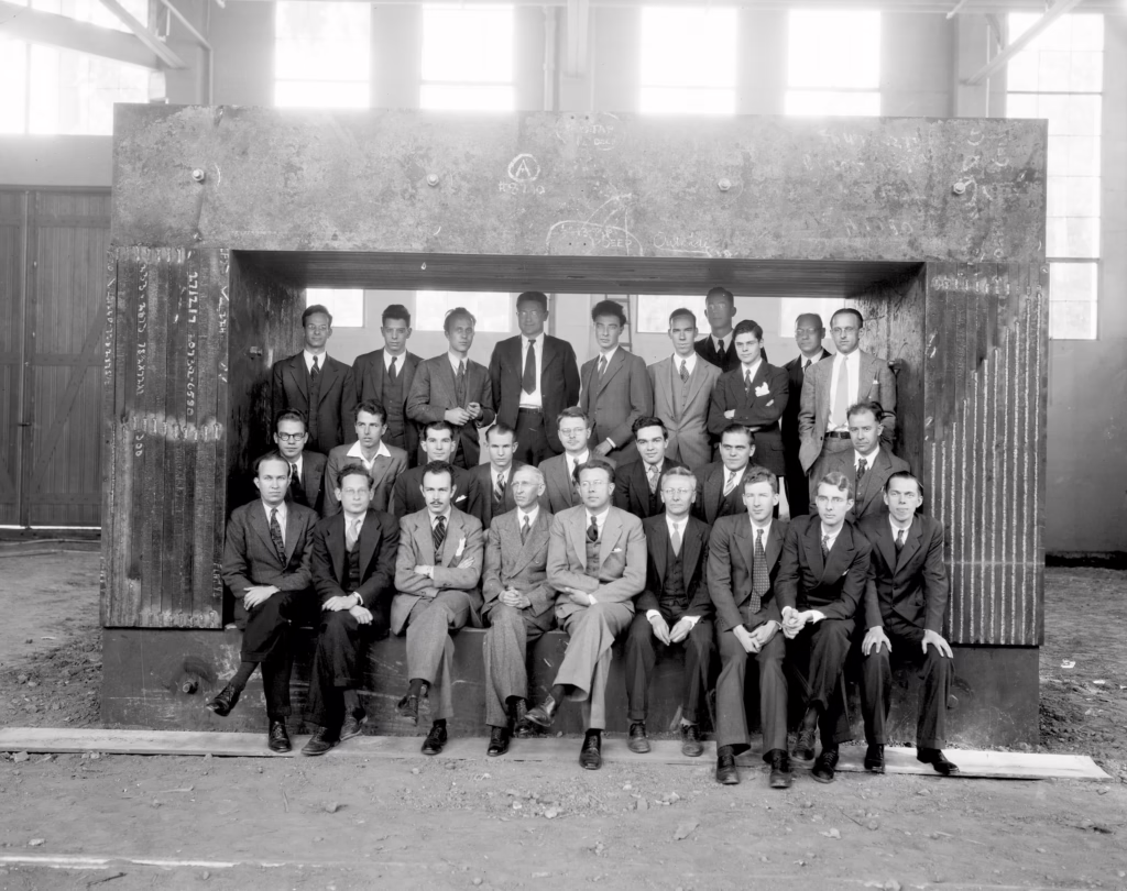 John H. Lawrence (first row, leftmost) amongst the early 'University of California Radiation Laboratory' staff, framed by the magnet for the 60-inch cyclotron, 1938